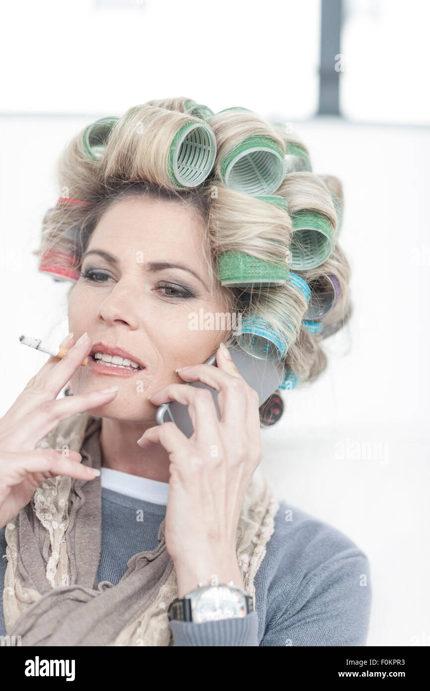Portrait of woman with hair curlers smoking a cigarette