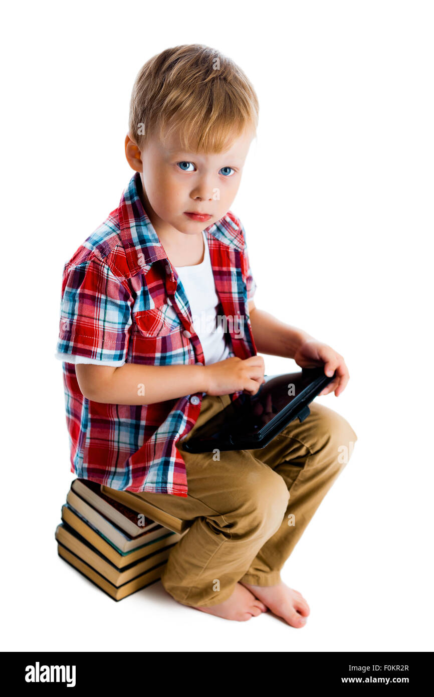 Little boy with a tablet computer sitting on the books on a white ...