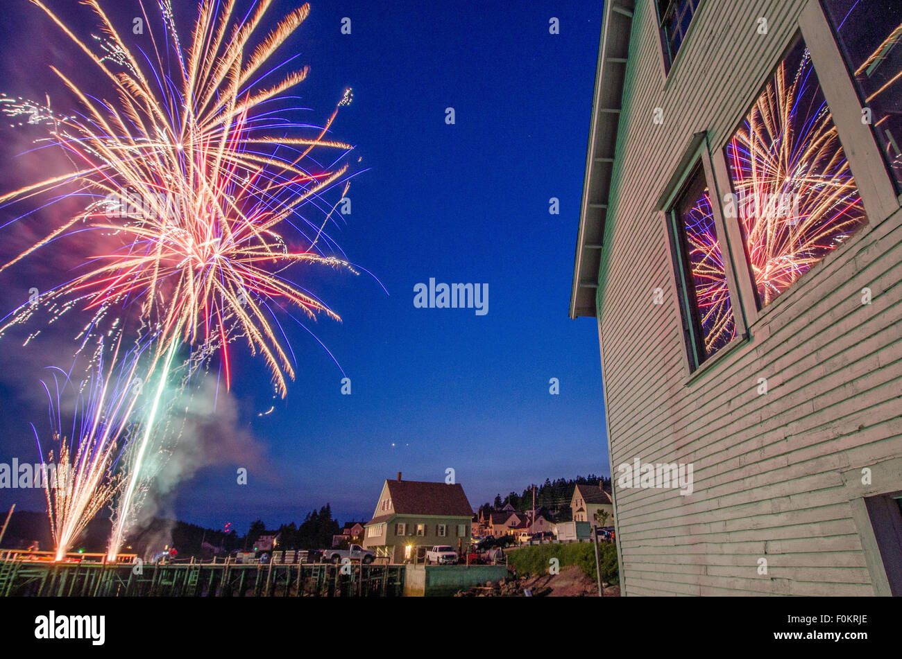 July 4th fireworks explode over a harbor on the Maine coast in celebration of Independence Day. Stock Photo