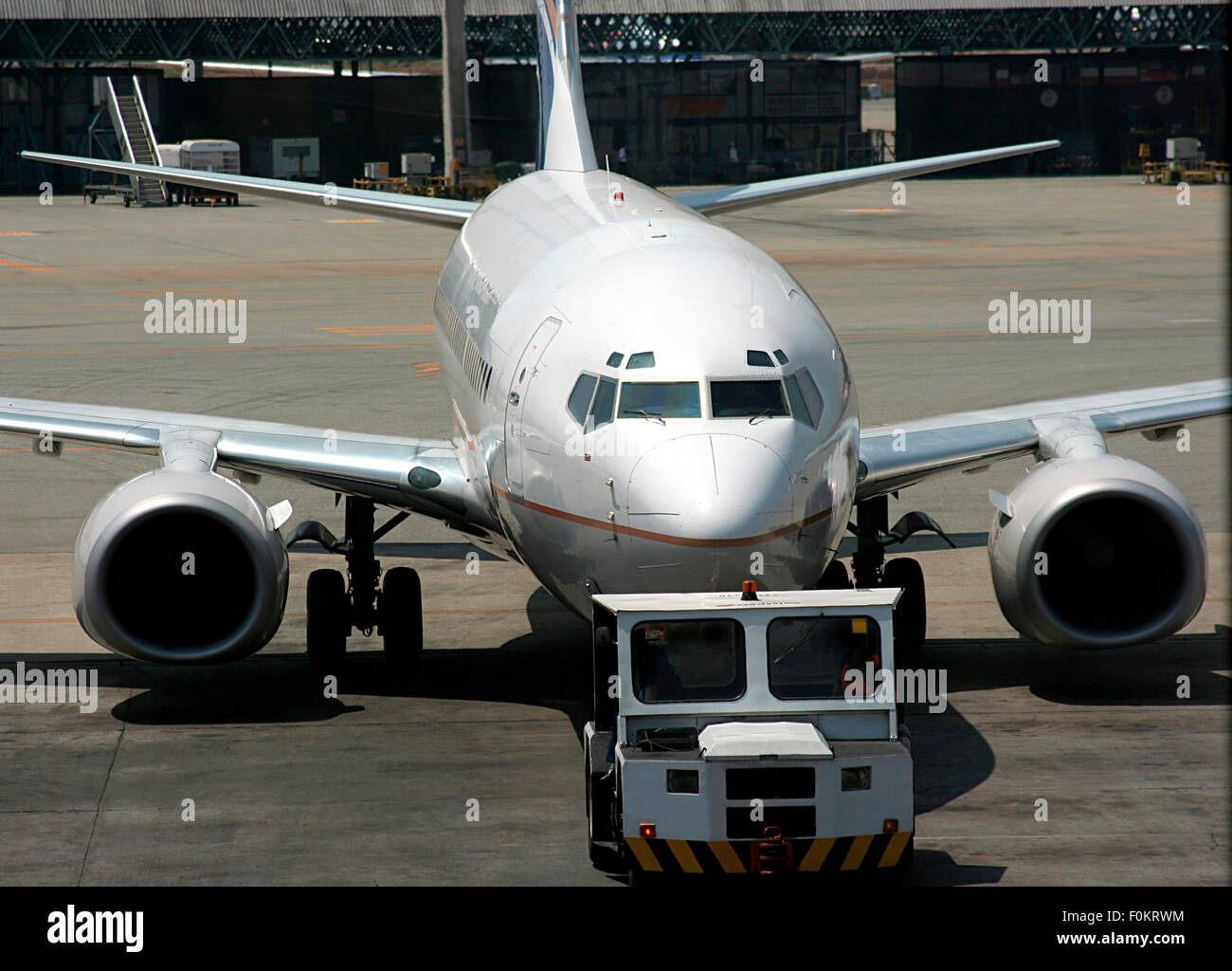 Passenger plane being pulled into the ramp at an airport Stock Photo