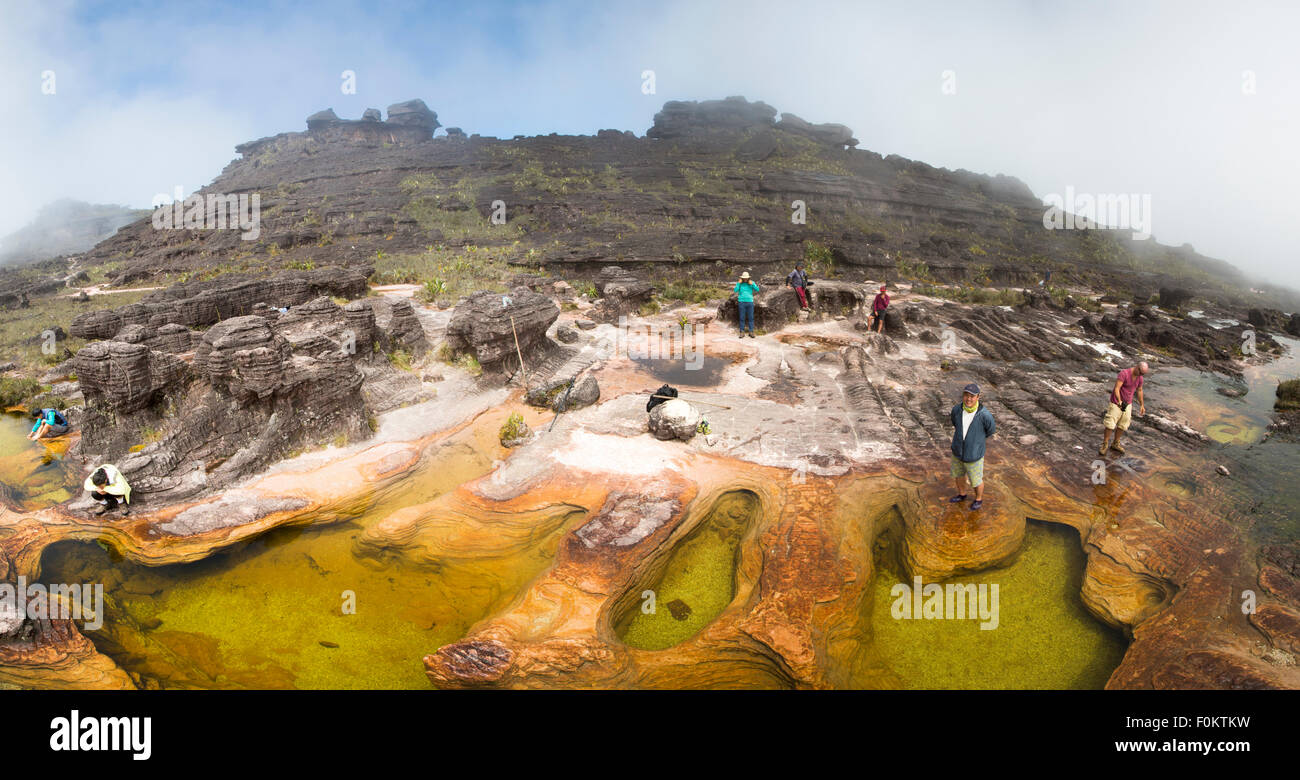 Panorama of group of hikers at the natural rock formations on the top of Mount Roraima which serves as natural swimming pools. Stock Photo
