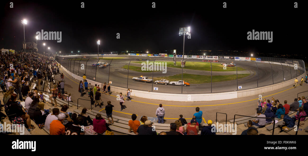 Unrecognizable people attending a stock car racing car at night. The