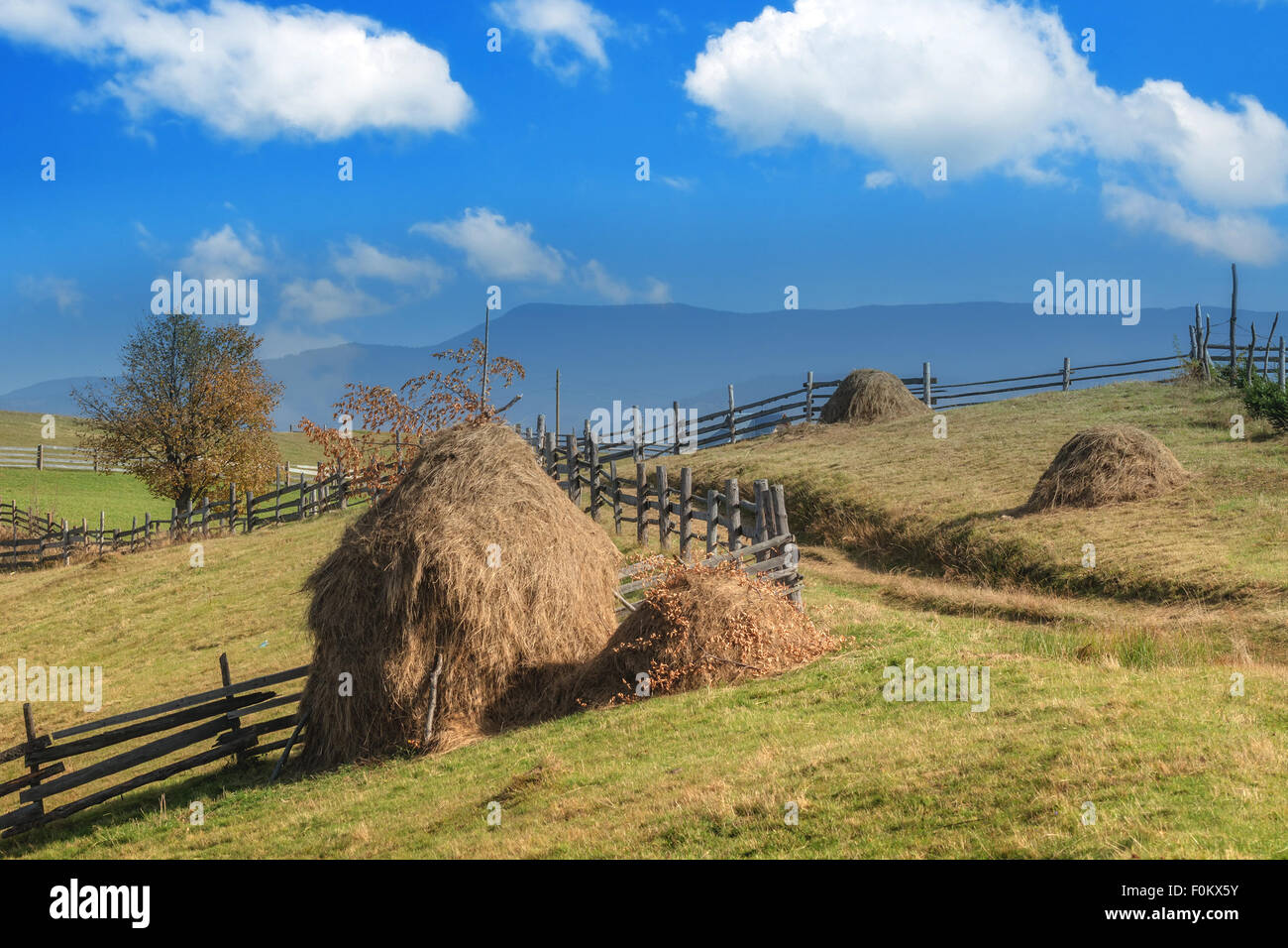 Amazing rural scene on autumn valley. Wooden fence and haystack on a foreground. Carpathians, Ukraine, Europe. Stock Photo