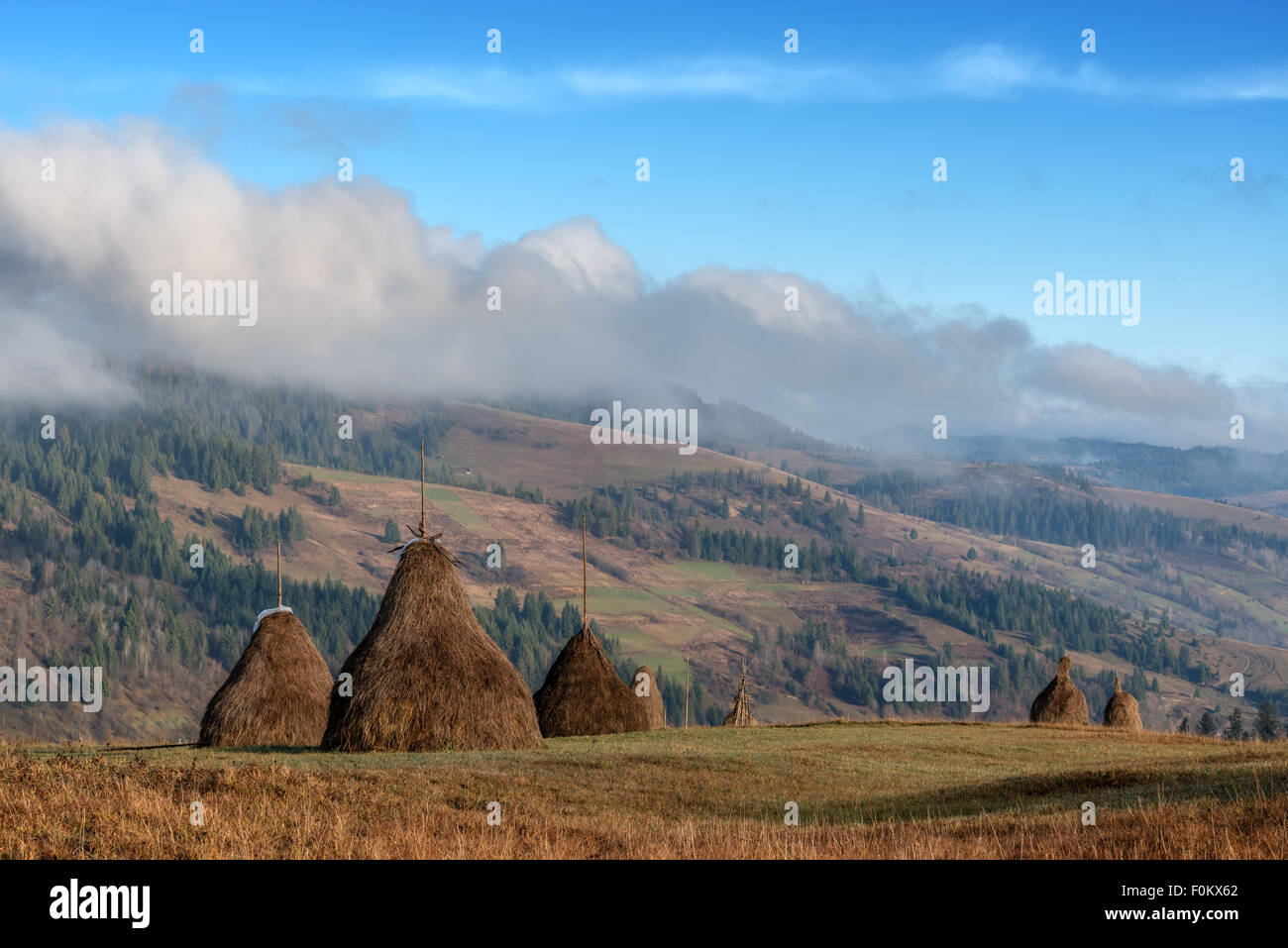 Amazing rural scene on autumn valley. Wooden fence and haystack on a foreground. Carpathians, Ukraine, Europe. Stock Photo