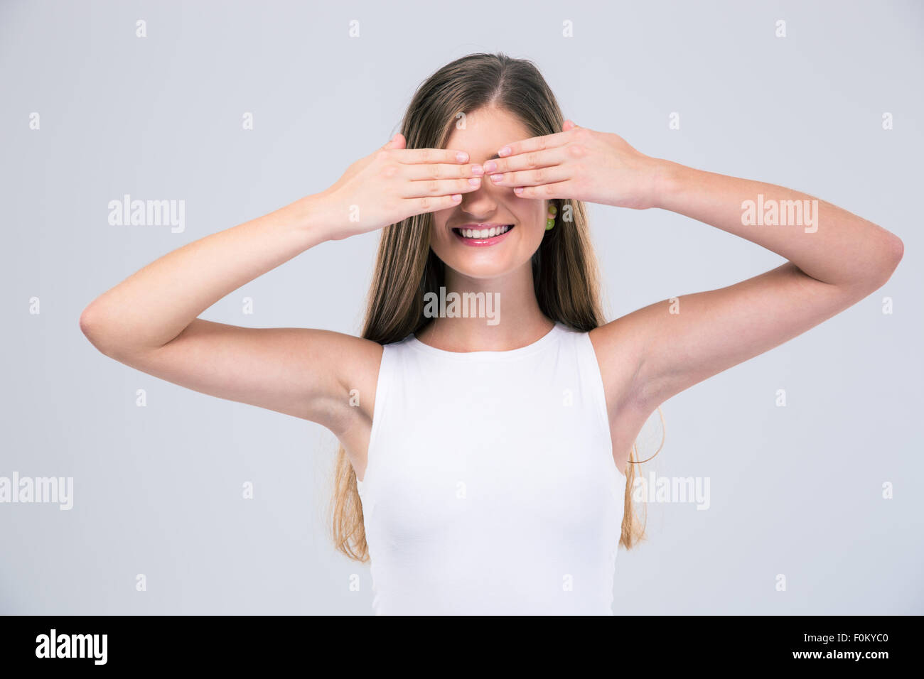 Portrait of a happy female teenager covering her eyes isolated on a white background Stock Photo