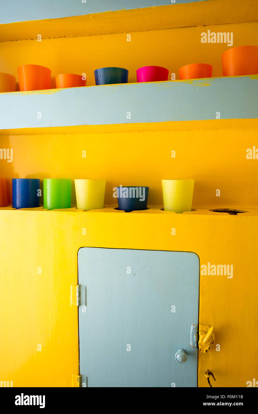 Plastic glass of various colors stored on yellow background Stock Photo