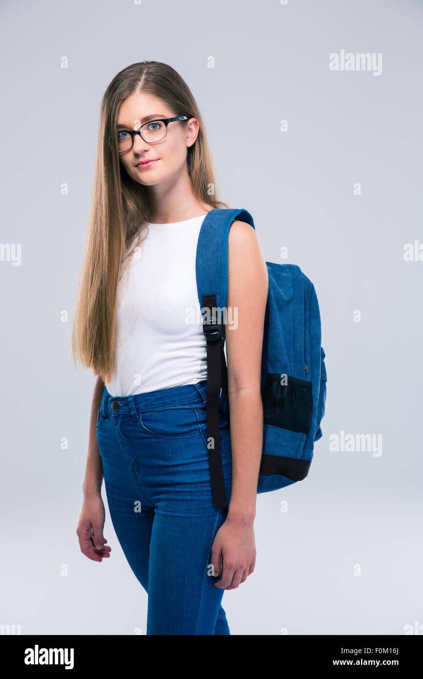 Portrait of a cute female teenager with backpack standing isolated on a ...