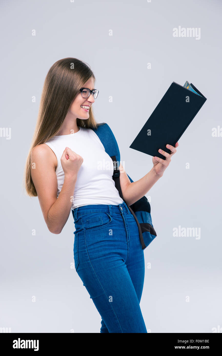 Portrait of a cheerful female teenager reading book isolated on a white ...
