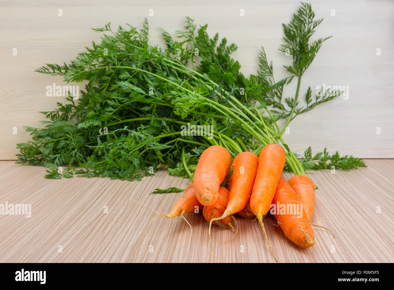 Fresh carrots with tops of vegetable on the wooden table Stock Photo