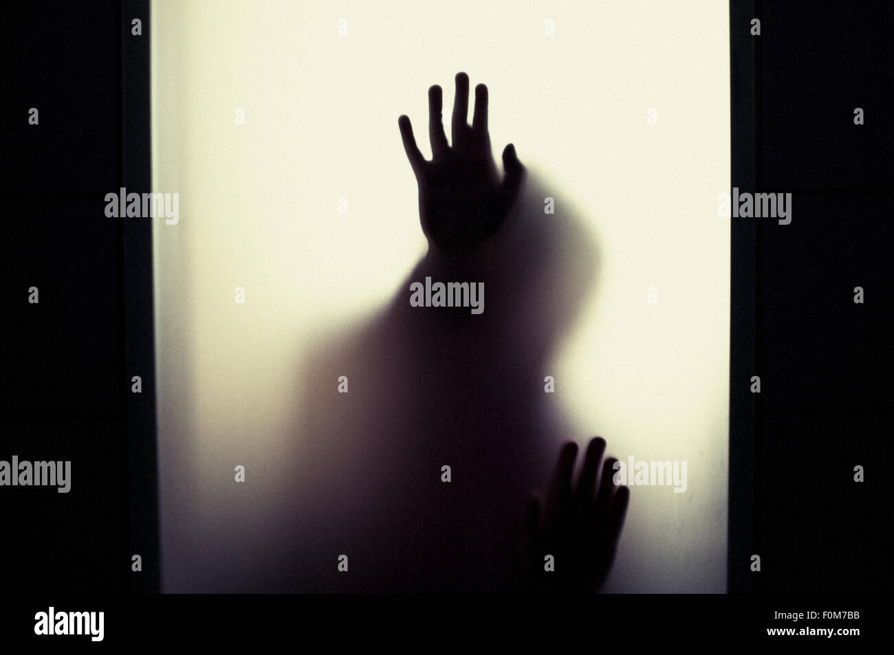 Silhouette of little child holding up hands. Conceptual image of childhood fears, abuse and safety of children. Stock Photo