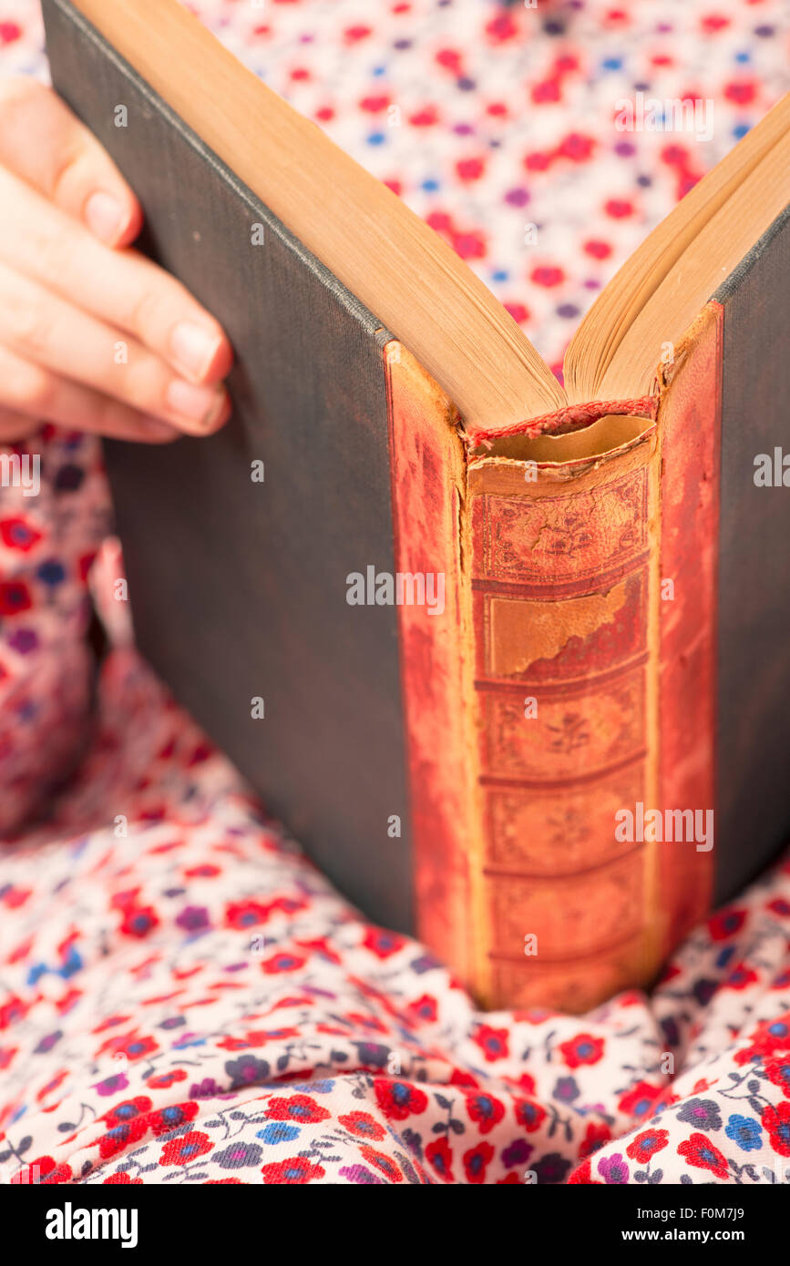 Little girl in dress reading in an old book. Conceptual image of learning to read at an early age. Stock Photo