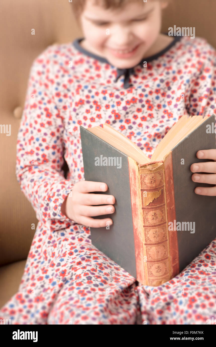 Little girl reading in an old book. Conceptual image of intelligence and learning to read at a young age. Stock Photo