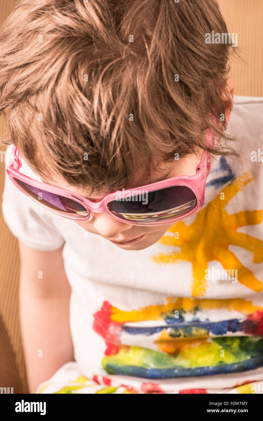Portrait of little girl with cool attitude. She is wearing pink sunglasses and looking down. Stock Photo