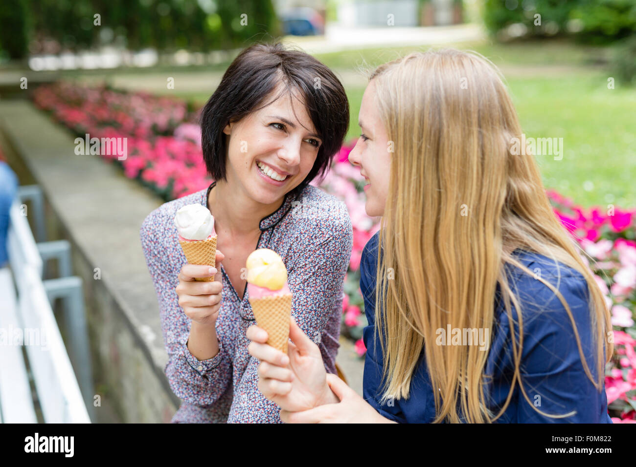 Two girlfriends laugh together and eating ice cream Stock Photo Alamy