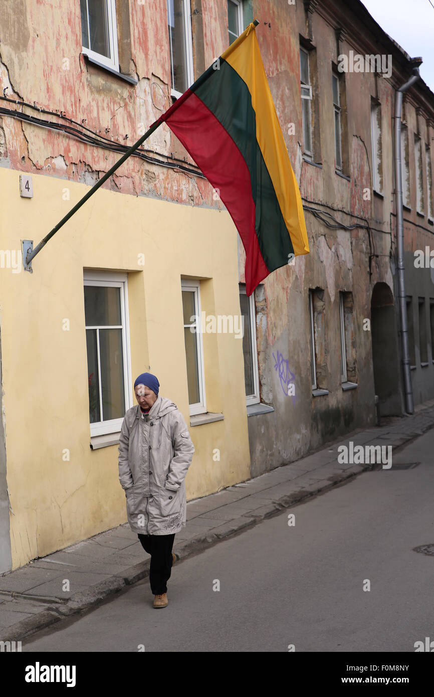 Old woman walking below Lithuanian national flag.Vilnius,Lithuania,Europe Stock Photo