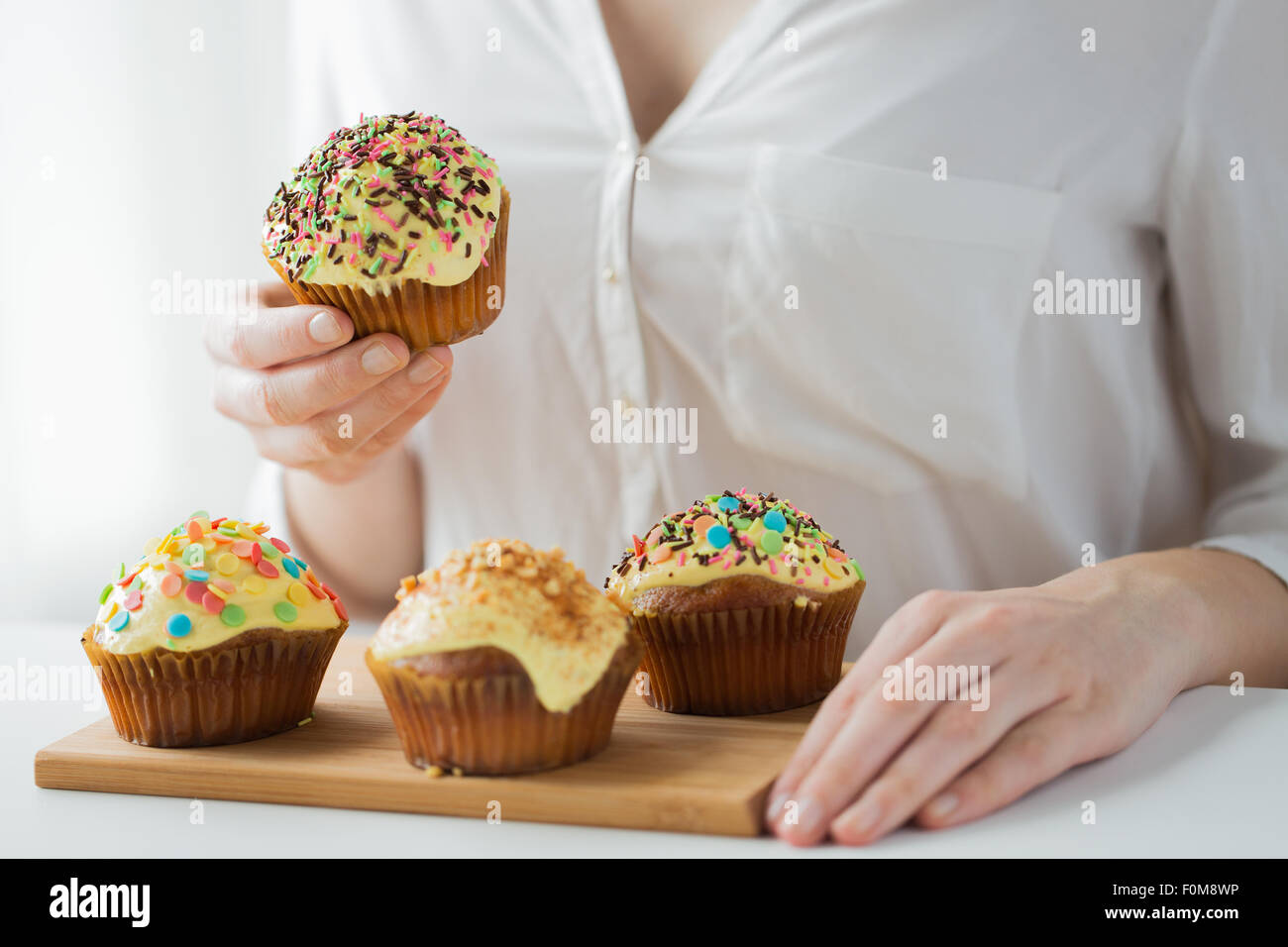 close up of woman with glazed cupcakes or muffins Stock Photo