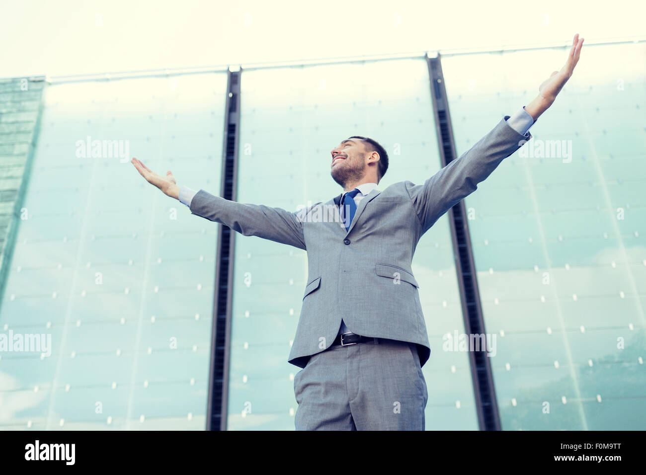 young smiling businessman over office building Stock Photo - Alamy