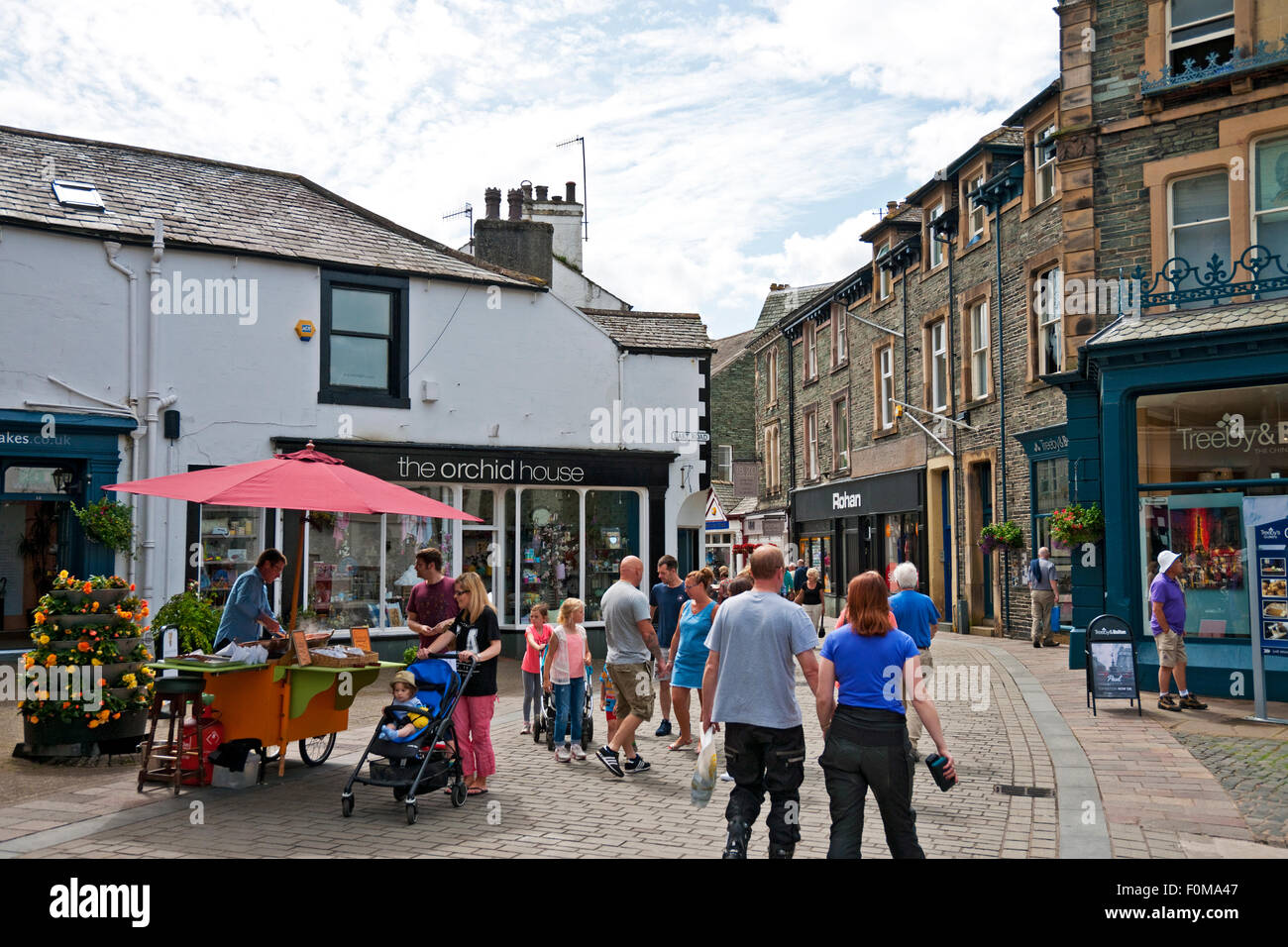 People tourists visitors walking by shops stores narrow street in