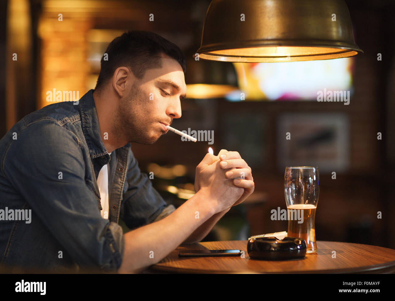 man drinking beer and smoking cigarette at bar Stock Photo Alamy