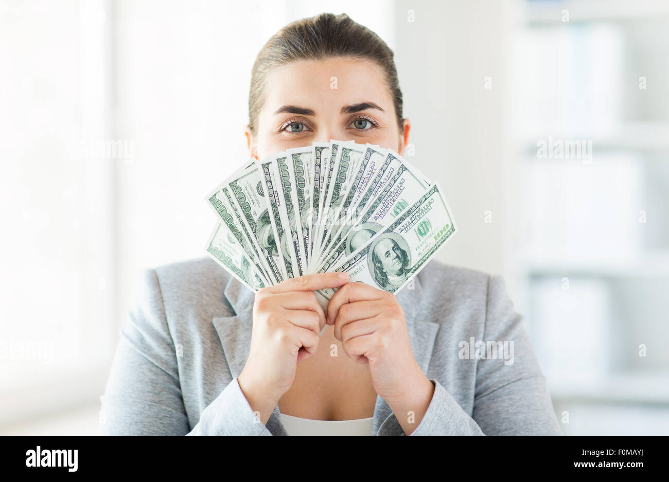woman hiding her face behind us dollar money fan Stock Photo
