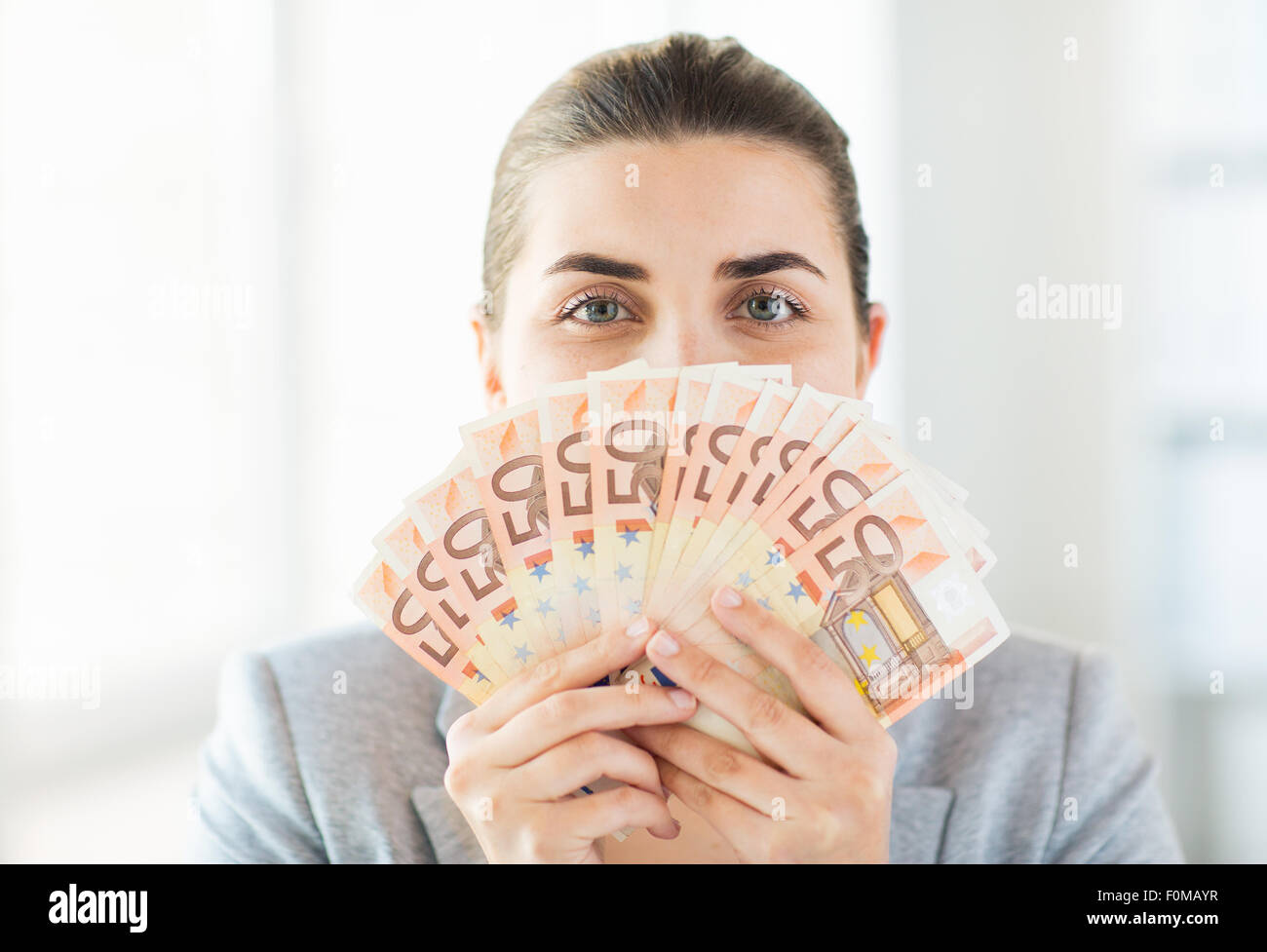 woman hiding her face behind euro money fan Stock Photo