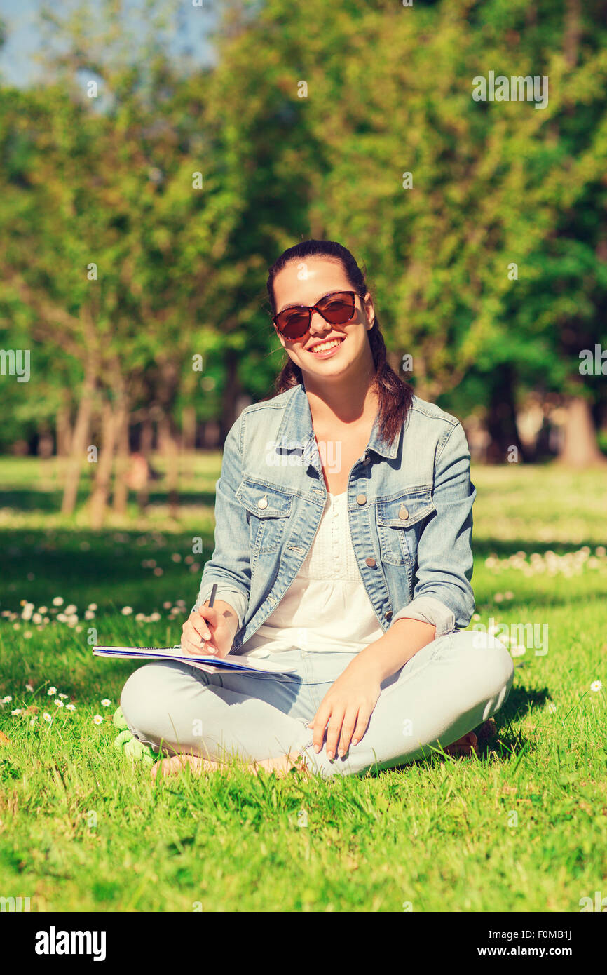 smiling young girl with notebook writing in park Stock Photo - Alamy