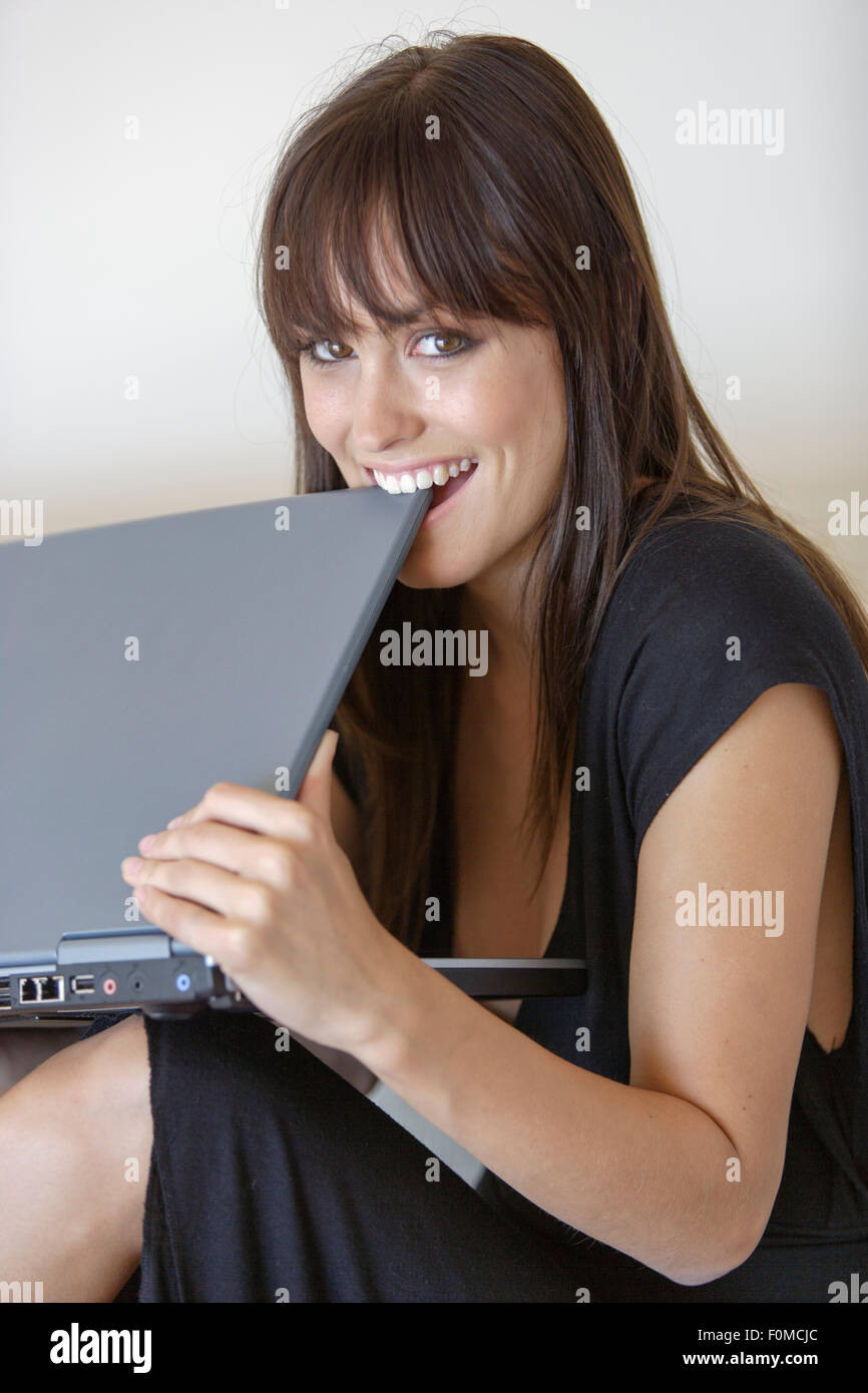 Young woman biting in Laptop computer Stock Photo