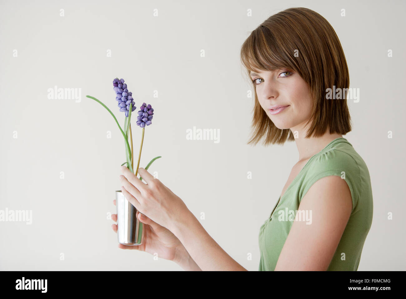 Young woman holding a plant in a studio Stock Photo - Alamy
