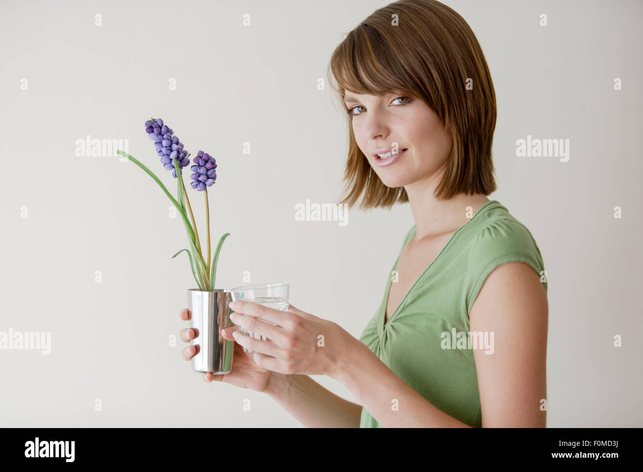 Young woman holding a plant in a studio Stock Photo - Alamy