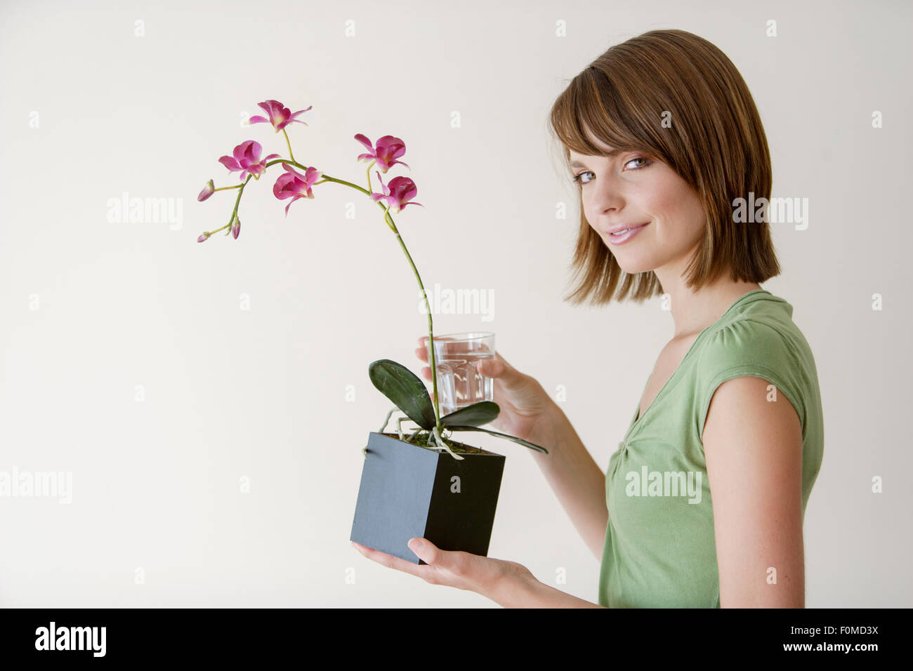 Young woman holding a plant in a studio Stock Photo - Alamy