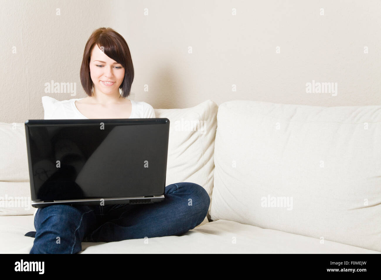 Young woman working on a laptop in her living room Stock Photo - Alamy