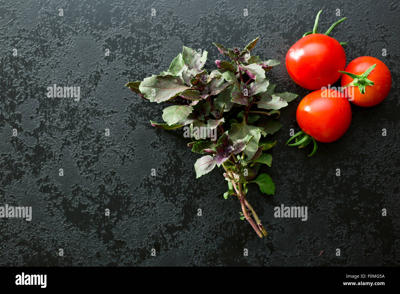 bunch of basil and tomatoes on black table Stock Photo - Alamy