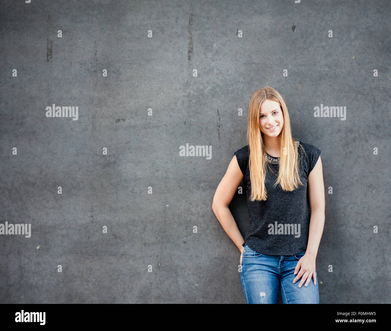 Attractive teenage girl standing in front of concrete wall Stock Photo