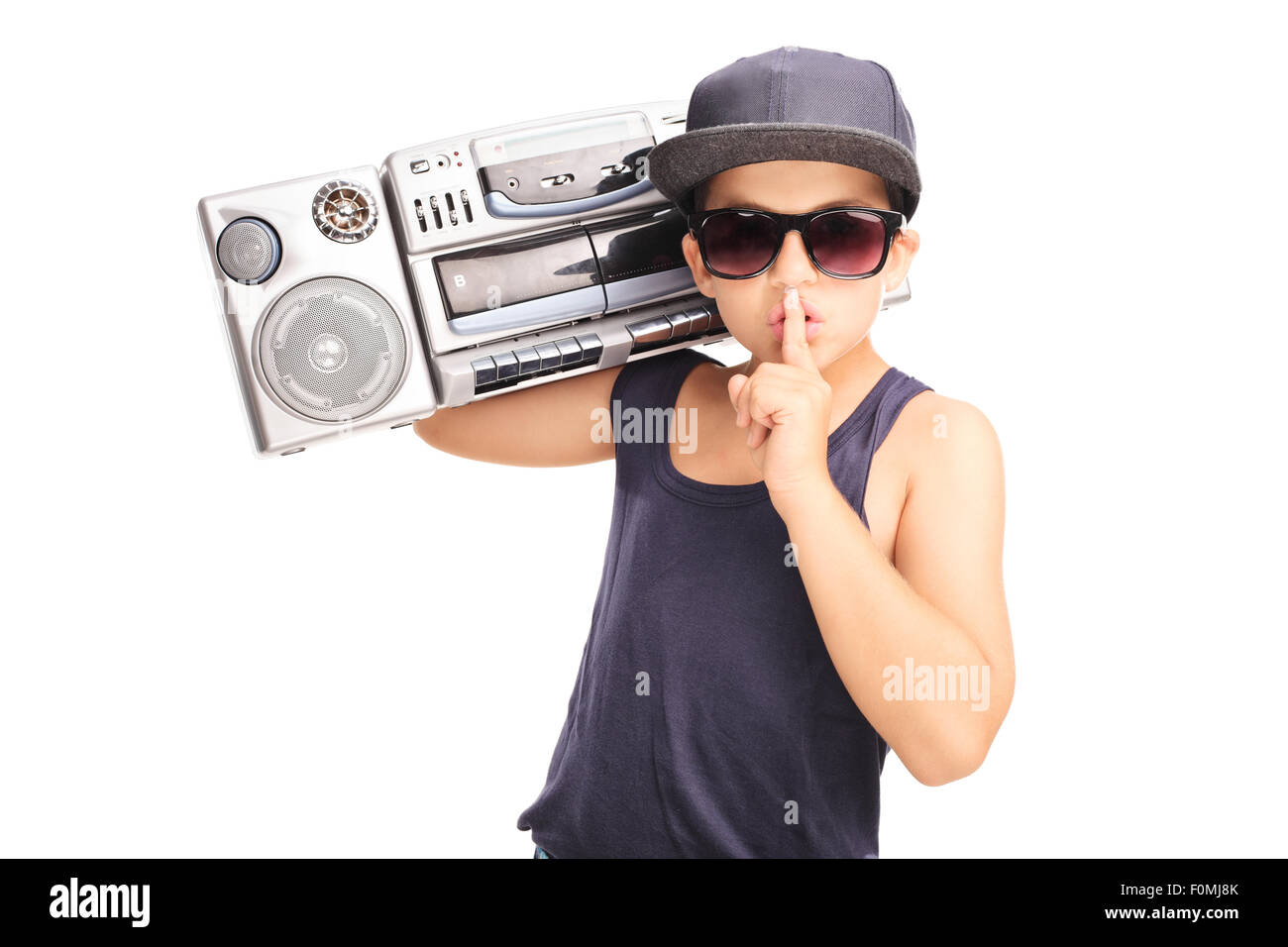 Little boy in hip-hop outfit carrying a ghetto blaster and holding finger on his lips isolated on white background Stock Photo