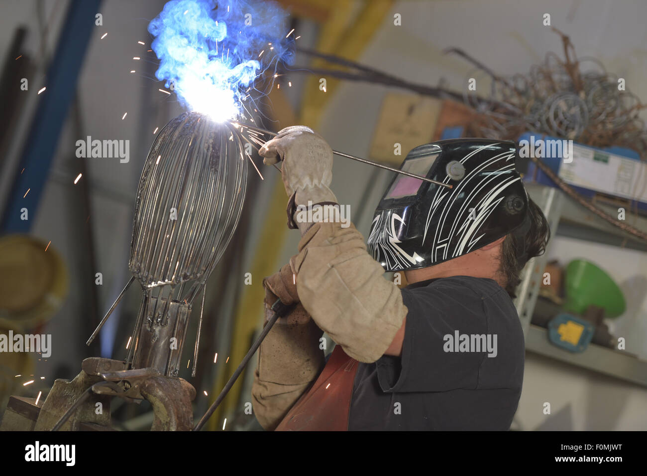Welder wearing face mask and protective gloves in factory Stock Photo