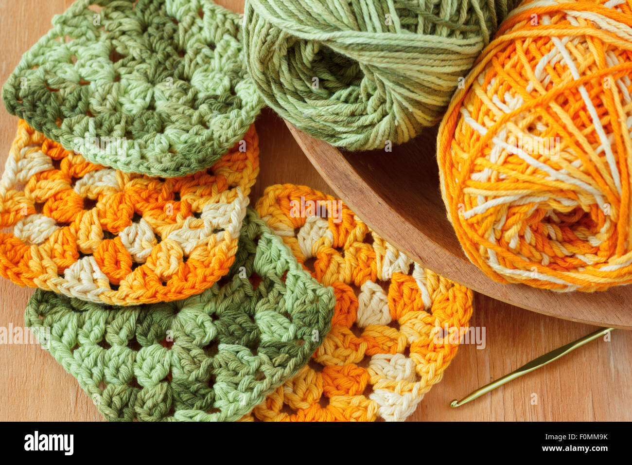 Handmade colorful crochet granny afghan square with skein on wooden