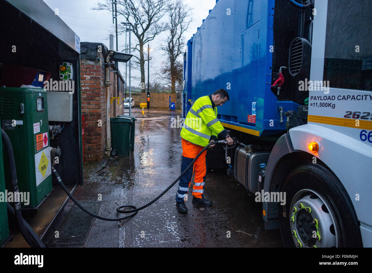 Driver fuels bin lorry with diesel at council depot. Stock Photo