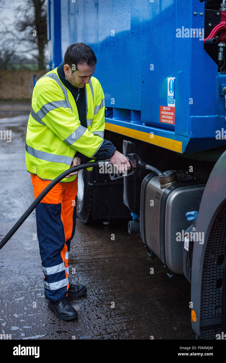 Driver fuels bin lorry with diesel at council depot. Stock Photo