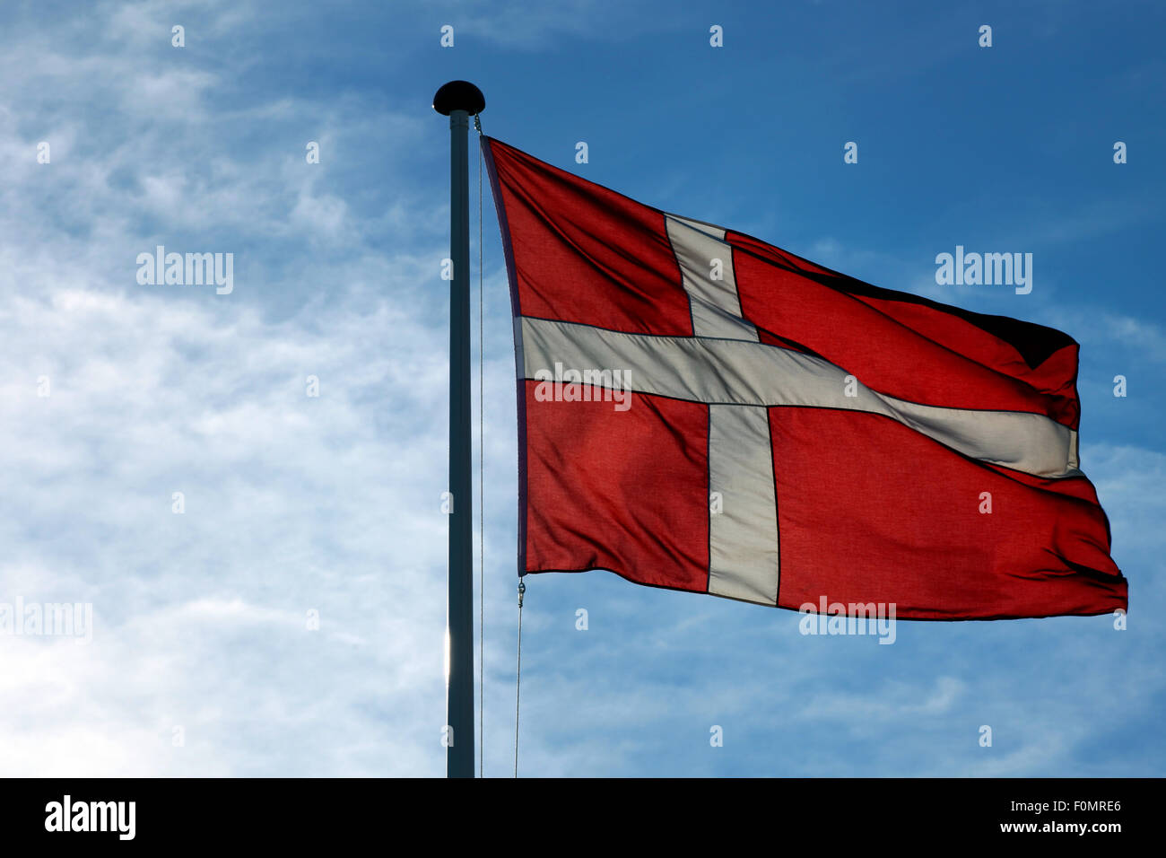 The Danish flag Dannebrog waving against blue sky Stock Photo