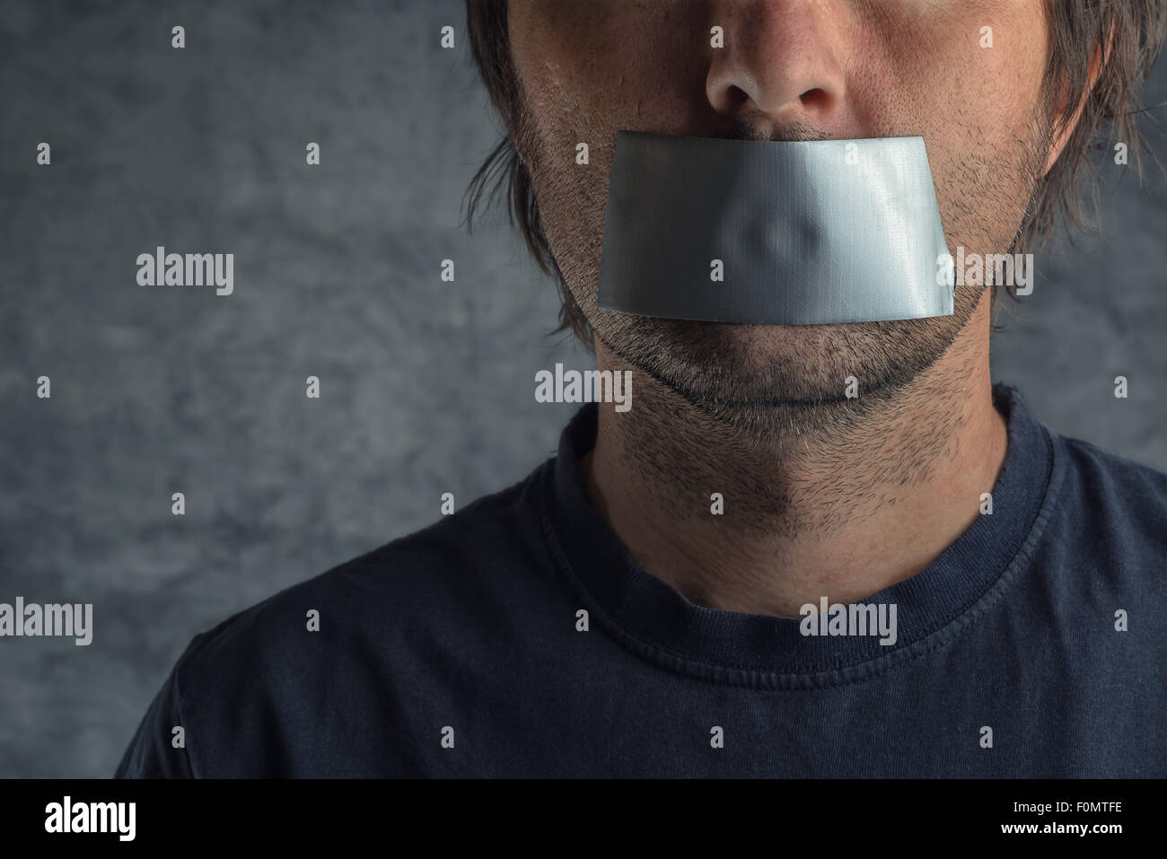 Censorship, adult caucasian man with duct tape on mouth to prevent him from speaking, freedom of speech and expression concept Stock Photo