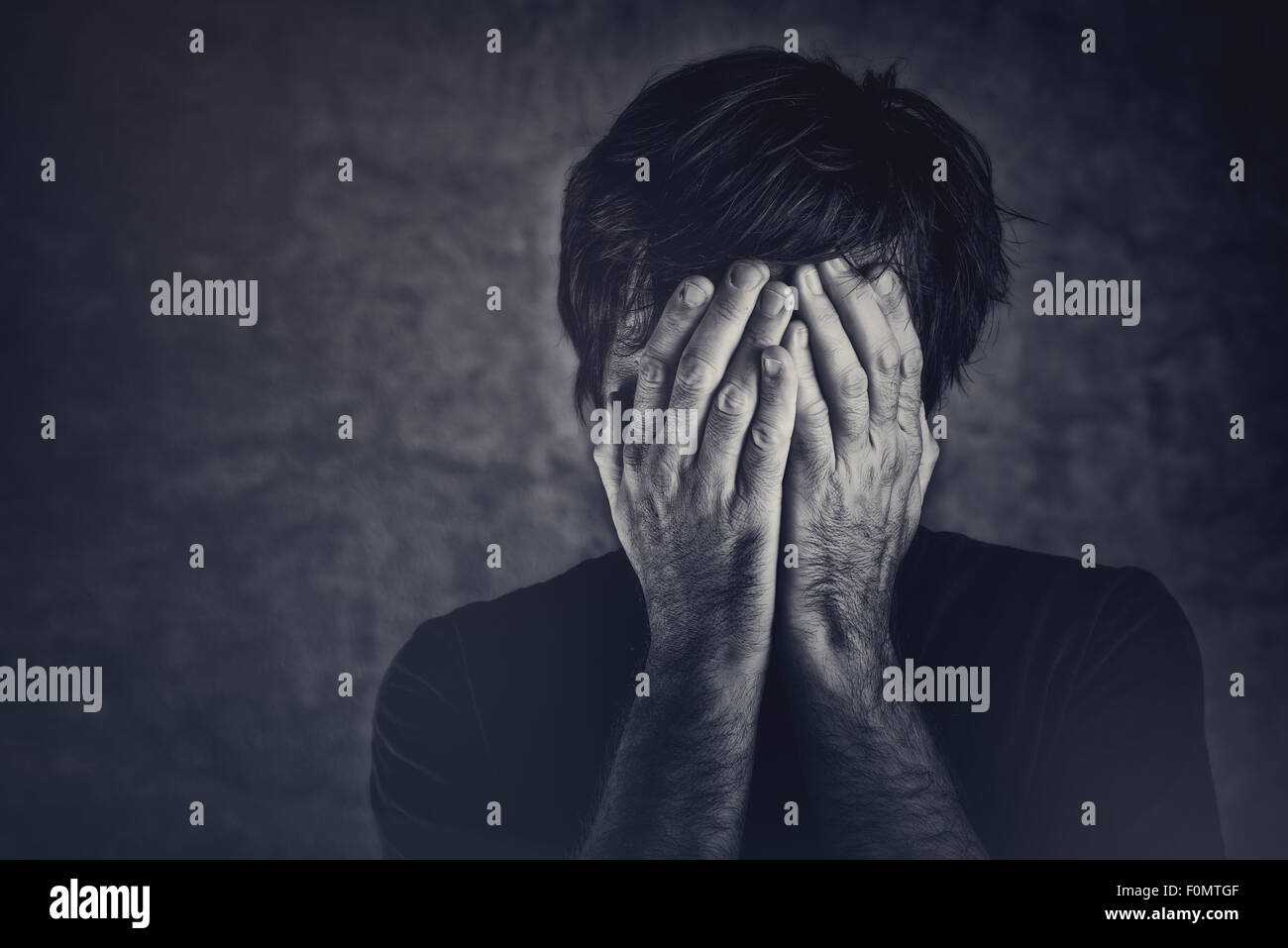 Grief, man covering face and crying, monochromatic image Stock Photo