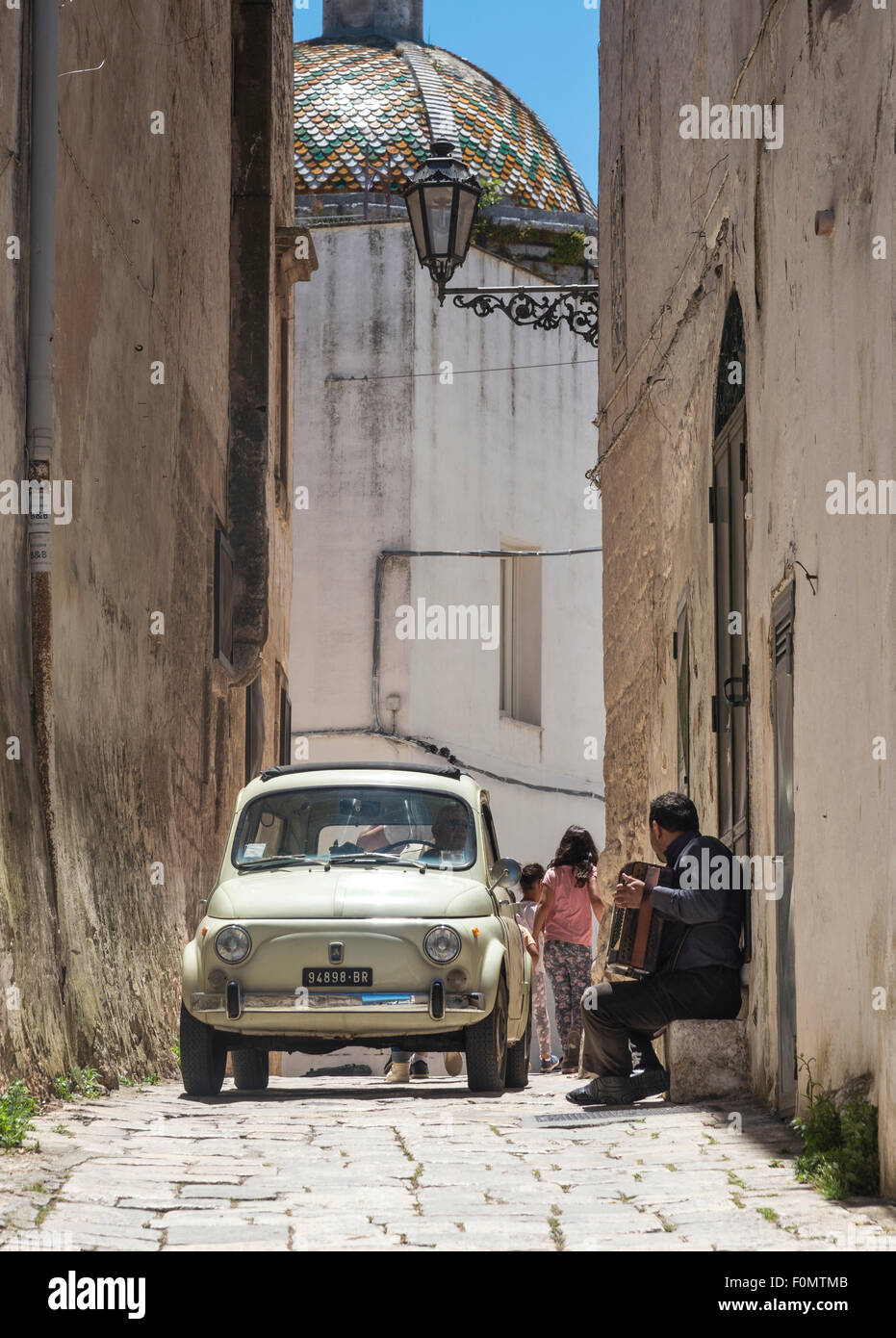 A busking accordianist and a fiat 500 meet in the back streets of Ostuni, Puglia, Italy Stock Photo