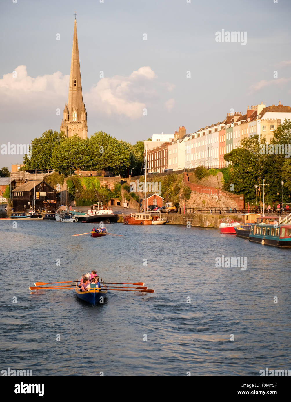 A view towards Redcliffe as gig rowers row on the floating harbour in Bristol in evening sunlight Stock Photo