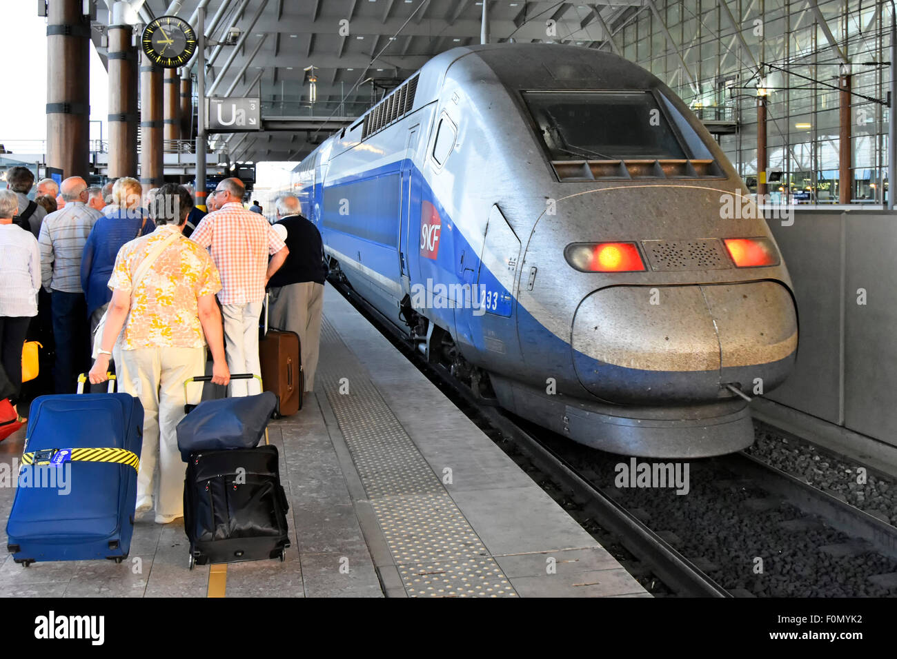 Aix-en-Provence France TGV train station & disembarked holiday passengers with luggage leaving platform as high speed TGV train departs French station Stock Photo