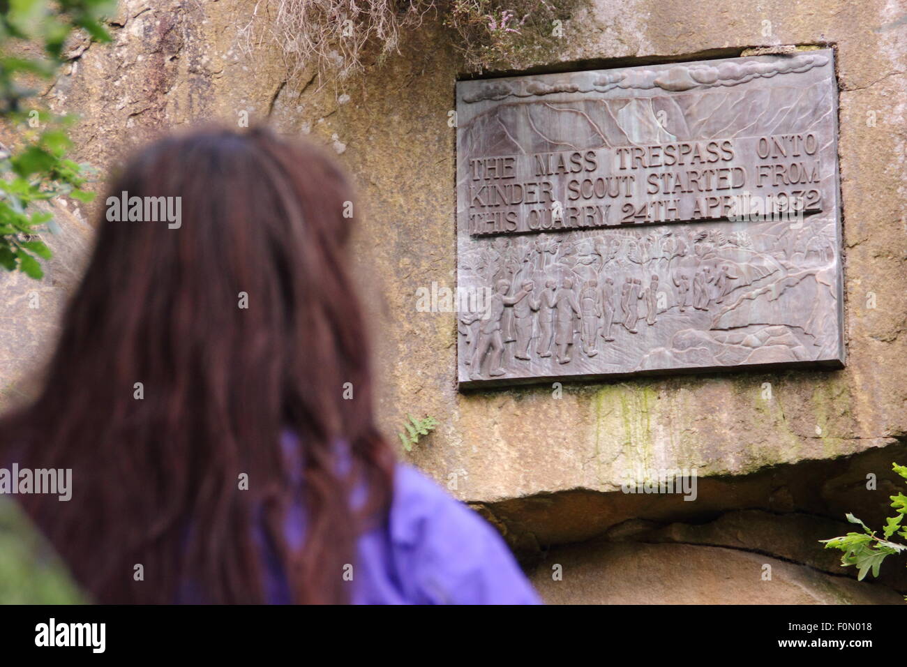 A female walker inspects the plaque in Bowden Bridge quarry that commemorates the mass trespass of Kinder Scout, Derbyshire UK Stock Photo