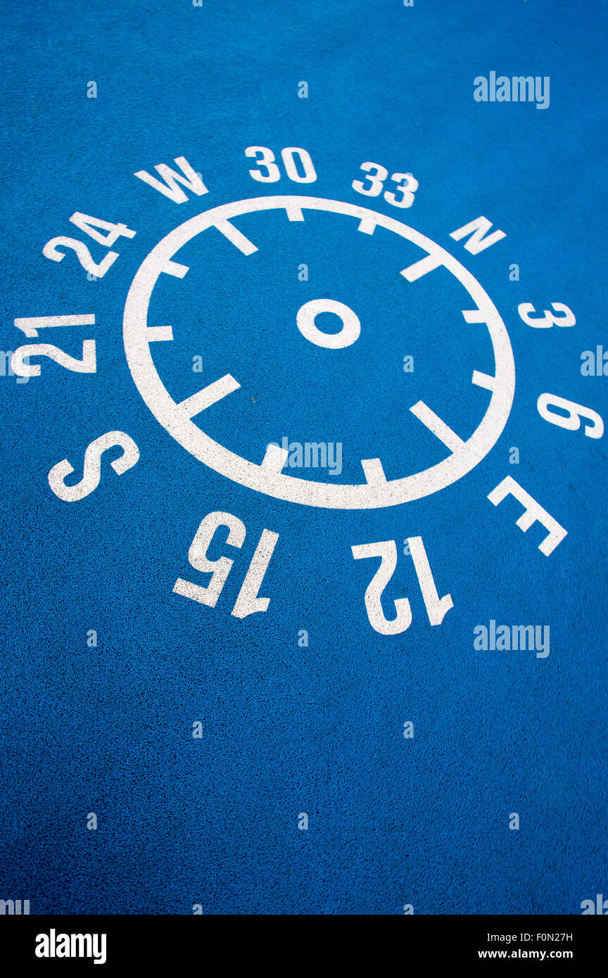 White shape of compass printed with coordinates and numbers on a blue clean concrete floor. Stock Photo