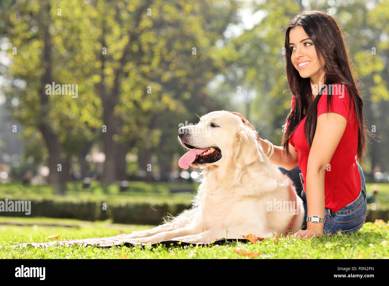 Beautiful girl sitting on the grass with her dog in a park Stock Photo ...