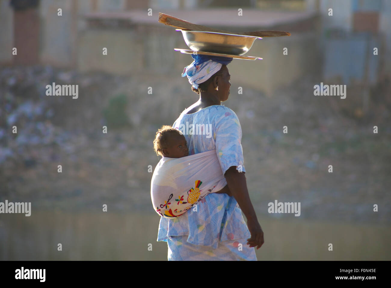 Unidentified Woman carrying a baby in her back in the streets of Mopti