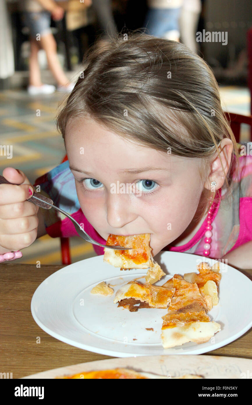 little beautiful girl eating pizza in pizzeria Stock Photo