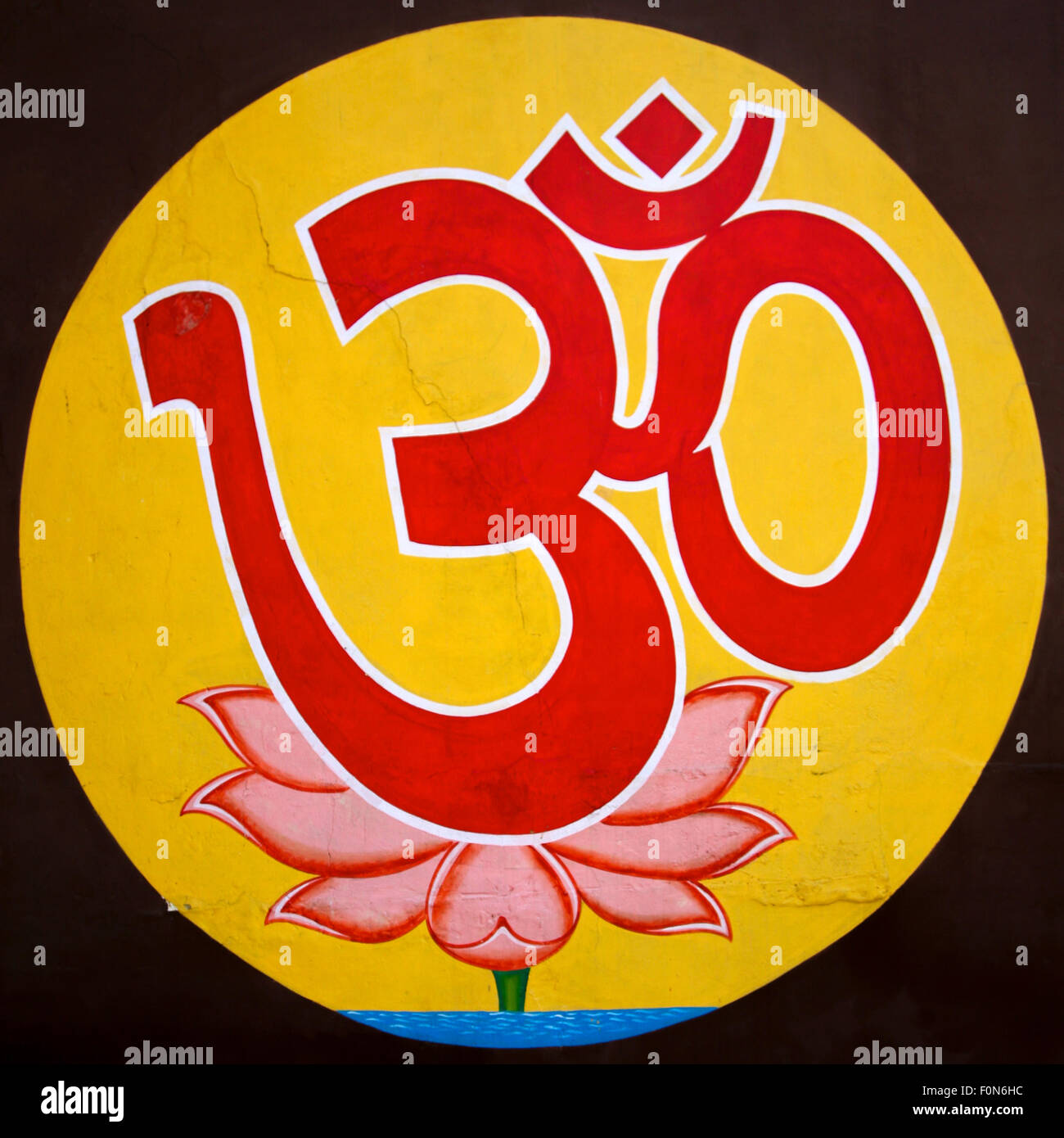 Yellow Aum (Om) the holy symbol on dark background taken on a wall in Varanasi, India. Stock Photo